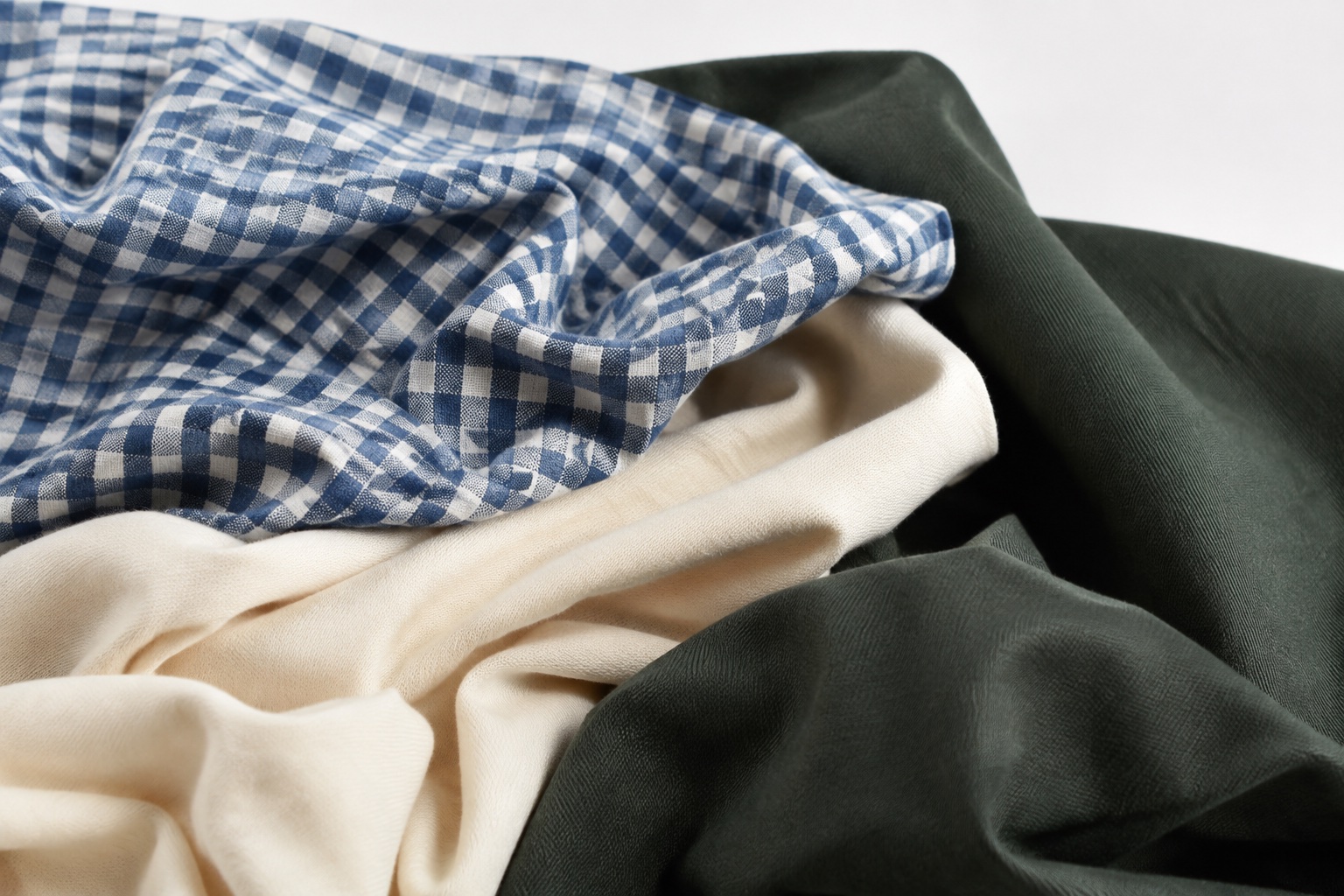 Indigo gingham, ivory knit, and forest green fabric in soft folds